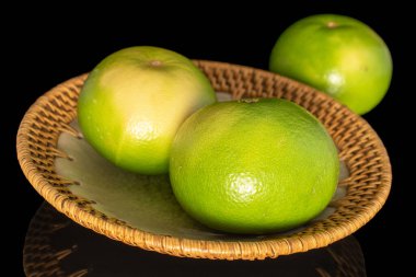 Three ripe organic Citrus Sweetie with a ceramic plate, close-up, isolated on a black background.
