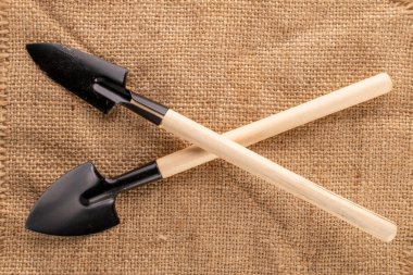 Garden tool with wooden handle on jute cloth, macro, top view.