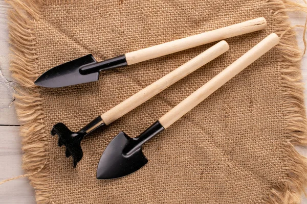 Garden tool with wooden handle on jute cloth, macro, top view.