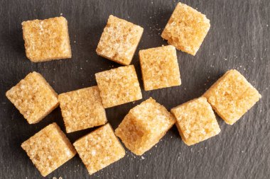 Several cubes of brown sugar, close-up, on a slate board, top view.