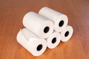 Several paper rolls of cash register tape on office desk, close up.