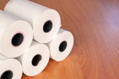 Several paper rolls of cash register tape on office desk, close up.