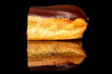 One half of a chocolate eclair, macro, isolated on a black background.
