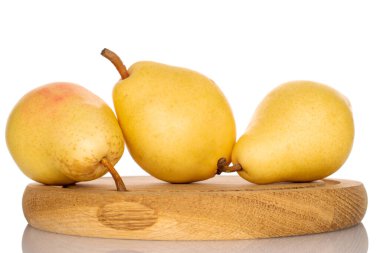 Three natural yellow pears on a wood board, close-up, isolated on white.