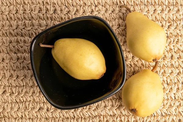 Three Organic Yellow Pears Black Plate Close Straw Mat Top — ストック写真