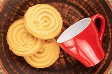 Çamur tabağında üç tatlı kurabiye, kırmızı bardak, makro, üst manzara..