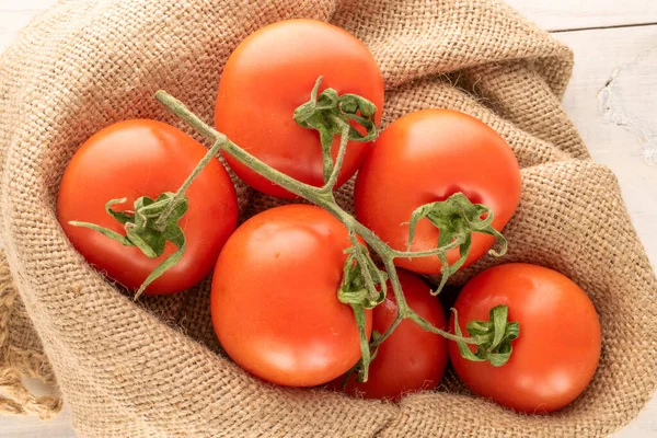 Kilka Świeżych Pomidorów Gałązce Jałowym Worku Drewnianym Stole Makro Widok — Zdjęcie stockowe