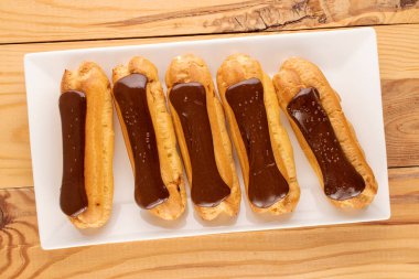 Tahta masa üzerinde beyaz seramik tabağı olan birkaç çikolatalı ekler, yakın plan, üst manzara..