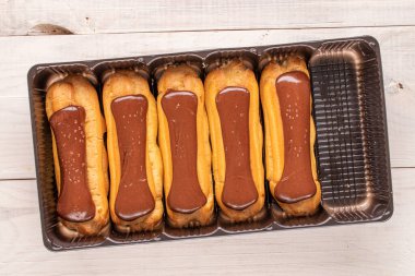 Tahta masanın üzerinde plastik tepsi olan birkaç çikolatalı ekler, yakın çekim, üst manzara..