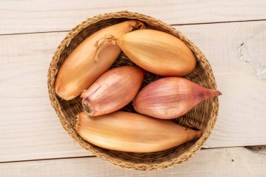 Tahta bir masada saman tabaktaki birkaç organik soğan, makro, üst manzara..