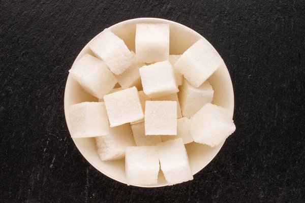 スレート石 マクロ トップビューに白いセラミックソーサーといくつかの白い砂糖キューブ — ストック写真
