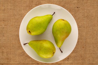 Üç organik armut, jüt kumaş üzerinde seramik plaka, makro, üst manzara..