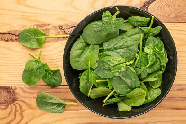 Fresh Green Spinach Leaves Black Ceramic Plate Wooden Table Macro — Stock Photo, Image