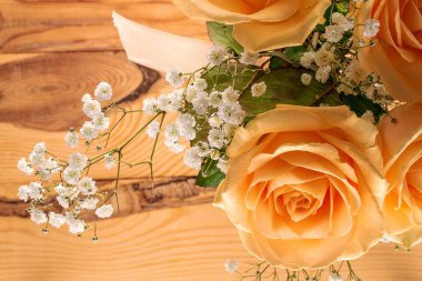 Biraz yumuşak. Krema gülleri ve tahta bir masanın üzerinde bir tutam çingene ağacı, makro, üst görünüm..