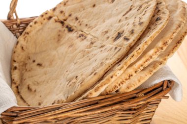 Tahta bir masanın üzerinde, yakın plan, üzüm sepetli taze pişmiş pide ekmeği..