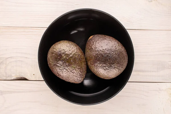 Twee Rijpe Avocado Met Zwarte Keramische Plaat Houten Tafel Macro — Stockfoto