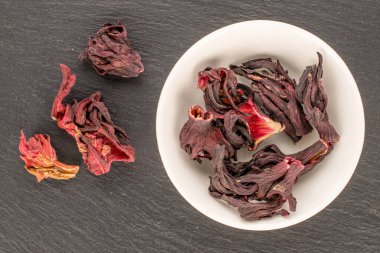 Kuru kokulu karkade çayı beyaz bir çay tabağı ile kayrak taşı, makro, üst manzara.