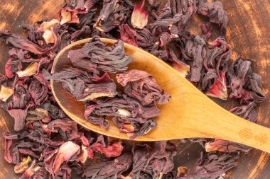 Kil tabakta ahşap kaşıkla kuru kokulu karkade çayı, makro, üst manzara..
