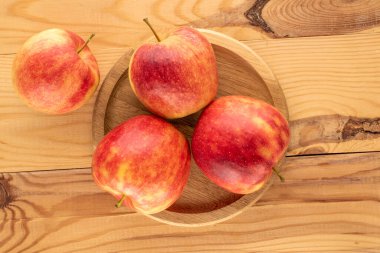 Tahta bir masada ahşap tepsiyle dört organik kırmızı elma, makro, üst manzara..