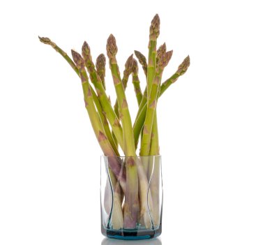 Cam bir şişede, beyaz arka planda izole edilmiş birkaç organik kuşkonmaz sapı..