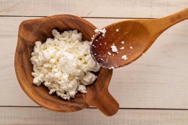 Tahta bir fincanda taze süzme peynir, ahşap bir masada kaşık, makro, üst manzara..