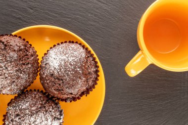 Üç ev yapımı çikolatalı kek, seramik sarı çay tabağı ve kayrak taşı, makro, üst manzara..