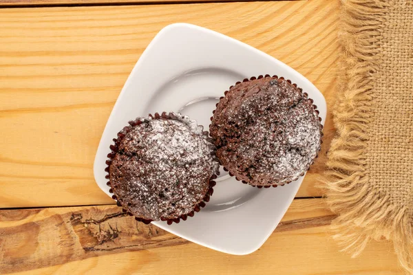 Dva Domácí Čokoládové Muffiny Bílém Keramickém Talíři Jutovým Ubrouskem Dřevěném — Stock fotografie