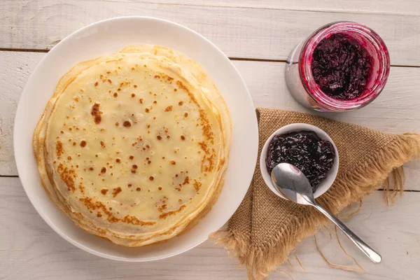 Seramik tabaklı birkaç tatlı krep ve ahşap masaya reçel, makro, üst manzara.