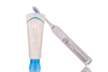 Bir plastik diş macunu tüpü ve bir elektrikli diş kalkanı, makro, beyaz arka planda izole edilmiş..