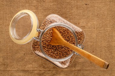 Karabuğday cam bir kabın içinde inliyor, tahta bir kaşıkla jüt kumaş, makro, üst manzara.