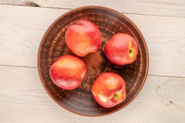 Tahta bir masada beyaz bir plaka ile dört olgun nektarin, makro, üst manzara..