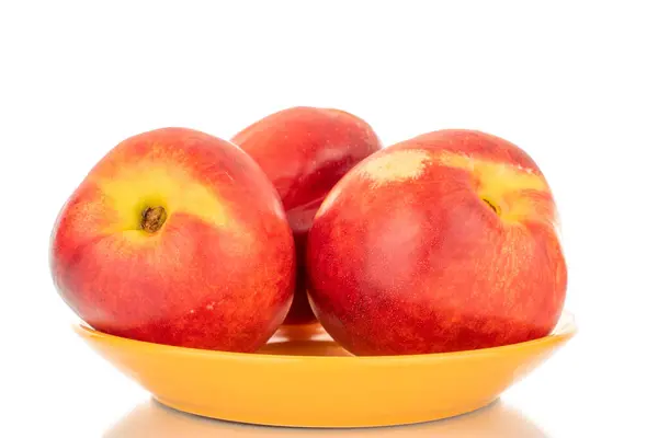 Stock image Three ripe nectarines on a ceramic saucer, macro, isolated on white background.