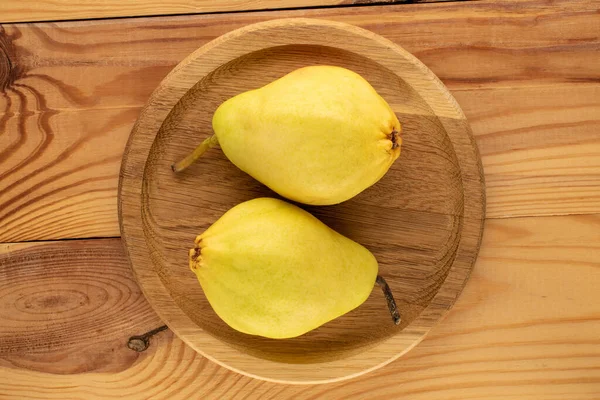 木製のテーブルの上に木製のトレイを持つ2つの明るい黄色の梨 マクロ トップビュー — ストック写真