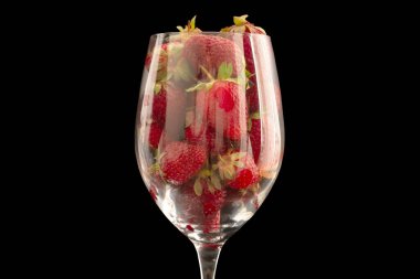 Cam bir kadehte kırmızı çilekler, makro, siyah arka planda izole edilmiş..