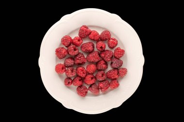 Beyaz seramik tabakta birkaç organik ahududu, siyah arka plan, makro, üst görünüm..