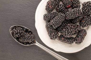 Beyaz seramik plakalı böğürtlen ve kayrak taşı, makro, üst görünümü metal kaşık..