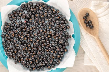 Tabaklı birkaç organik kuşüzümü, ahşap kaşık ve ahşap masa üzerine keten peçete, makro, üst manzara..