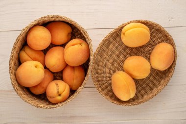 Tahta bir masada, makroda, kamış sepetinde bir sürü sarı kayısı..