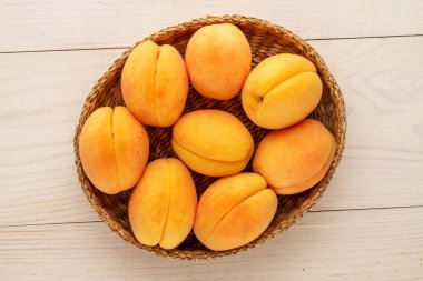 Tahta bir masada saman tabaktaki birkaç sarı kayısı, yakın plan, üst manzara..