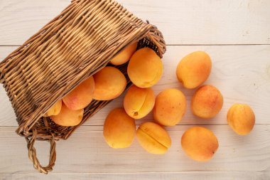 Tahta bir masada sepetin içinde birkaç sarı kayısı, makro, üst manzara..