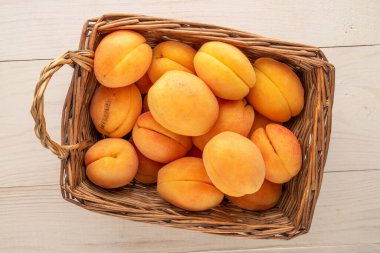 Tahta bir masada sepetin içinde birkaç sarı kayısı, makro, üst manzara..