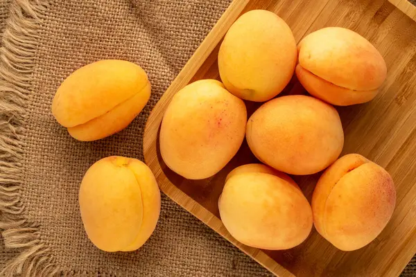 Olgun sulu kayısılar, bambu tepsiler, jüt kumaş, makro, üst manzara..