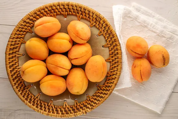 Tahta bir masanın üstünde seramik bir tabakta birkaç sulu kayısı, makro, üst manzara..