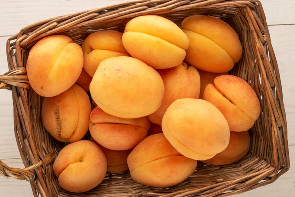 Tahta bir masada sepetin içinde birkaç sarı kayısı, makro, üst manzara..