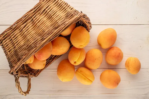 Tahta bir masada sepetin içinde birkaç sarı kayısı, makro, üst manzara..