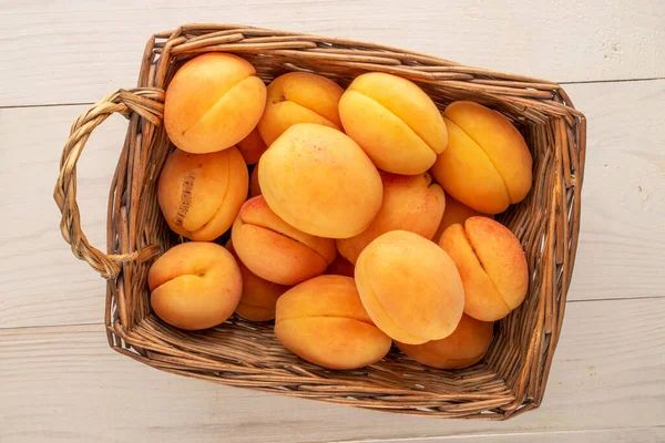 Tahta bir masada sepetin içinde birkaç sarı kayısı, makro, üst manzara..