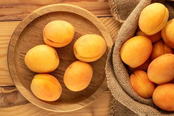 Tahta tepside, tahta masada, makroda ve üst manzarada birkaç sarı sulu kayısı..