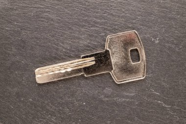 Bir kapı kilidi için bir anahtar bir taş levha üzerinde, yakın plan, üst görünüm.