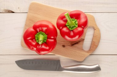 Ahşap mutfak tahtasıyla iki tatlı kırmızı biber ve tahta masa üzerinde bıçak, makro, üst manzara..