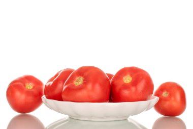 Beyaz seramik bir tabakta, beyaz arka planda izole edilmiş birkaç tane olgun kırmızı domates..